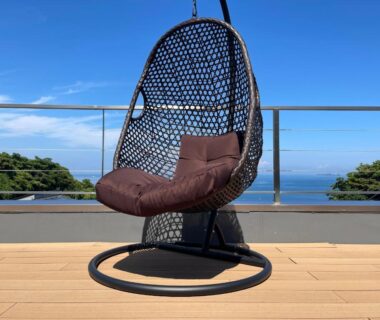 Hanging wicker chair on wooden balcony at StellaMarina~海の星 ATAMI with sea and treeline view