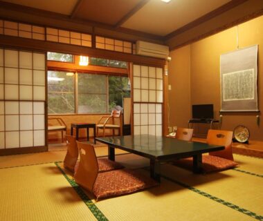 Traditional tatami room with low table, zabuton chairs, shoji screens and a tokonoma alcove at Suehirokan in Niigata