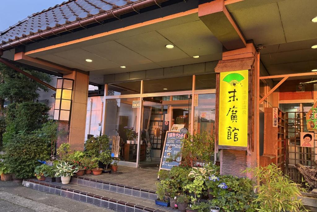 Entrance at Suehirokan Ryokan Niigata Lit entrance with signboard, potted plants and glass doors at Suehirokan in Niigata