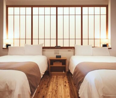 Minimal twin bedroom with shoji screens, wooden floor and bedside lamps at Sui Suwako in Nagano