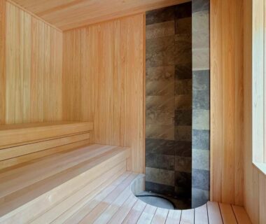 Wood-paneled sauna with tiered benches and vertical stone heater at Suigan in Hokkaidō