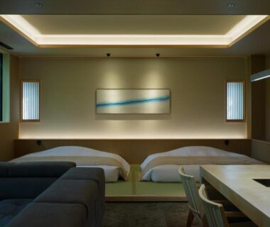 Spacious modern room with twin beds on tatami, sofa, dining table and soft ambient lighting