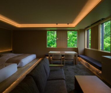Twin beds and sofa seating with greenery-filled windows at Suigan, Hokkaidō