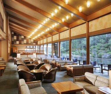 Ryokan lounge with sofas, wicker chairs and garden view at Suimeikan in Gifu