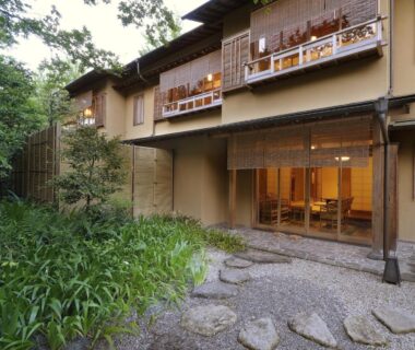 Traditional ryokan exterior with stone path, shoji screens, wooden balconies and landscaped garden at Suimeikan, Gifu