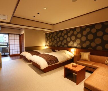 Spacious tatami room with two low beds, shoji screens and seating area at Suiun, Kanagawa, Japan