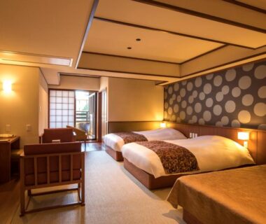 Warm tatami room with two low beds, shoji screens and seating area at Suiun in Kanagawa