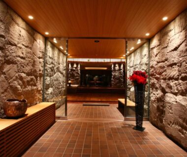 Stone-walled entrance corridor with wooden ceiling and flower arrangement at Suizantei Club Jozankei Hokkaidō Japan