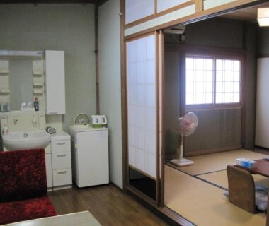 Tatami seating with low table, shoji screens, sink and mini fridge at Suminoe Ryokan in Hiroshima, Chūgoku