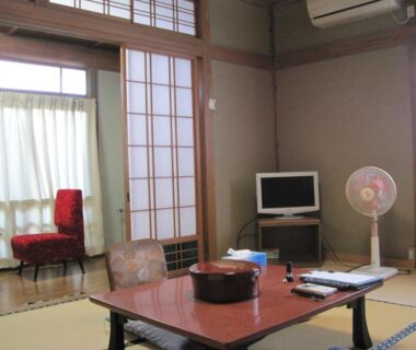 Tatami room with low table, shoji screens, TV and seating at Suminoe Ryokan in Hiroshima, Chūgoku