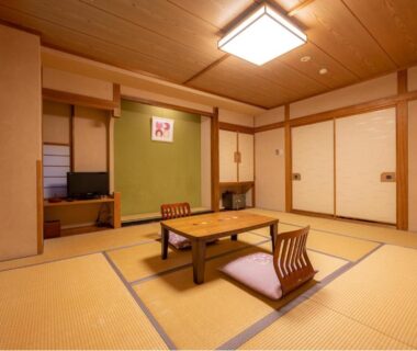 Traditional tatami room with low table, two floor chairs, shoji screens and alcove at Suminoyu, Nagano