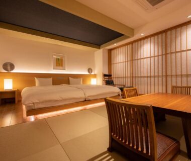 Japanese tatami room with low beds, shoji screens and wooden dining table at Suminoyu in Nagano
