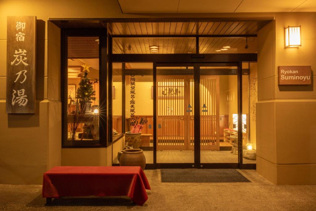Welcoming Ryokan Entrance Suminoyu Nagano Entrance with sliding glass doors, wooden interior panels, lanterns and red bench at Suminoyu in Nagano