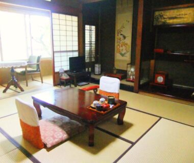 Traditional tatami room with low wooden table, zabuton cushions, shoji screens and tokonoma alcove at Sumiyoshi Ryokan in Gifu