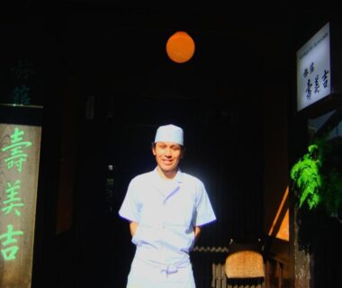Staff in white uniform at Sumiyoshi Ryokan entrance beside wooden sign and lantern, Gifu, Chubu, Japan