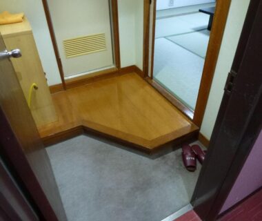 Traditional genkan with wooden step and slippers leading to tatami room at Sumiyoshiya, Niigata