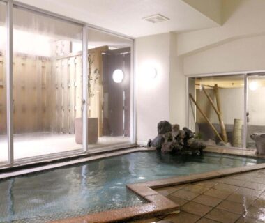 Indoor onsen bath with rock feature and glass wall at Sumiyoshiya Niigata