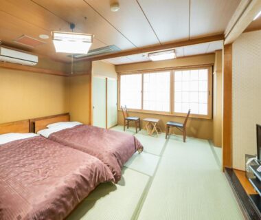 Bright tatami room with twin beds, shoji window, low table and chairs at Sumiyoshiya in Niigata, Chūbu