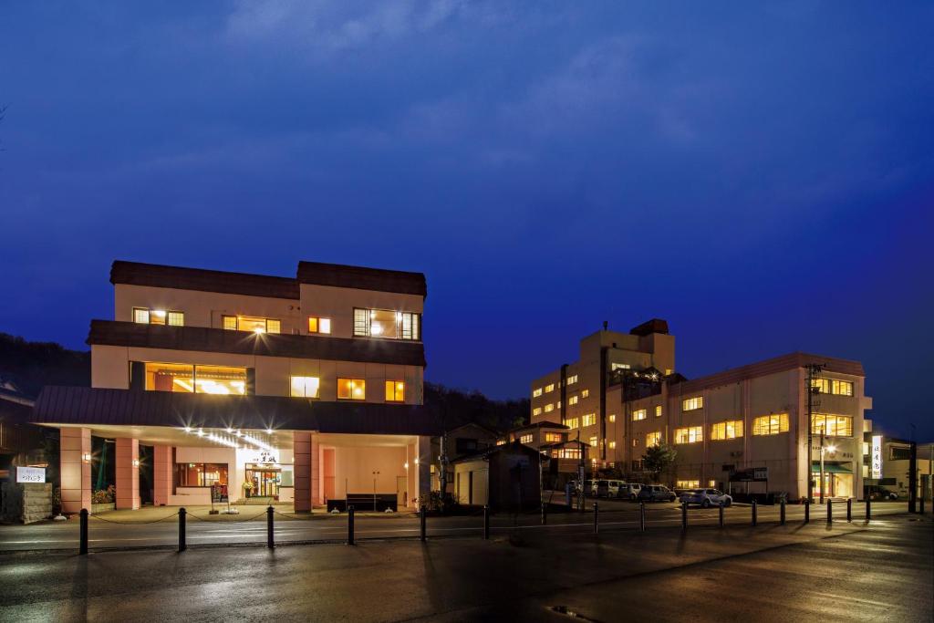 Evening exterior of Sumiyoshiya Ryokan Niigata Lit multi-story ryokan exterior at twilight with paved forecourt and warm interior lights, Sumiyoshiya in Niigata Prefecture