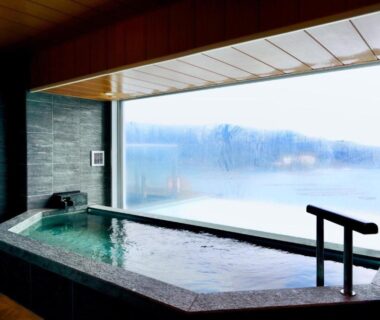 Stone indoor bath with expansive lakeside window at Sun Urashima Yuki no Sato in Mie prefecture