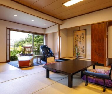 Tatami room with low table, zabuton cushions and shoji doors opening to garden at Sun Urashima Yuki no Sato, Mie