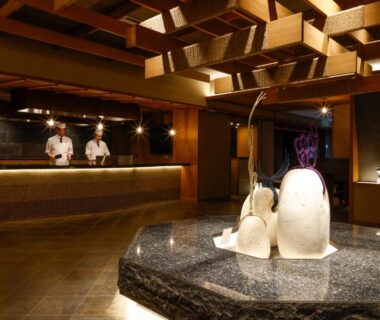 Lobby with stone water feature, wooden ceiling beams and reception at Sun Urashima Yuki no Sato, Mie