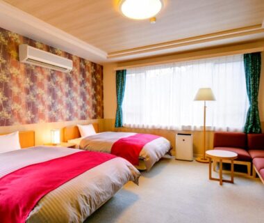 Bright twin room with two beds, patterned wallpaper, sofa seating and large curtained window at Sundance Resort Hakone Gora Kanagawa