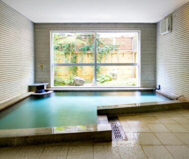Tiled indoor onsen with large window overlooking a small garden at Sundance Resort Hakone Gora Kanagawa