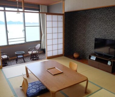 Tatami room with low table, shoji screens and balcony chairs overlooking the sea at Sunrise Katsuura, Wakayama