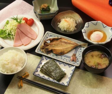 Traditional Japanese breakfast with grilled fish, rice, miso soup, nori and assorted side dishes on tray