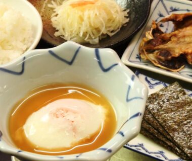 Soft-cooked egg with grilled fish, rice, nori and salad on breakfast tray at Sunrise Meiji-ya, Nagano