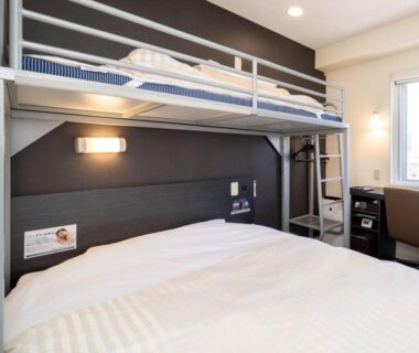 Modern compact room with bunk bed over double bed, ladder, desk and window at Super Hotel Asahikawa Hokkaido