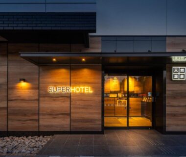 Illuminated wooden entrance with glass doors of Super Hotel Asahikawa in Hokkaidō