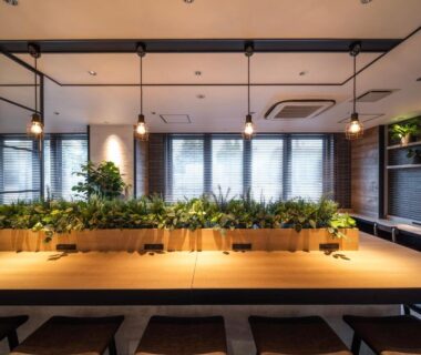 Long wooden communal table with pendant lights at Super Hotel Asahikawa in Hokkaidō, Japan