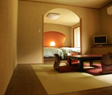 Traditional tatami room with low table, floor cushions and futon beds in alcove at Yado Kanzan, Gunma