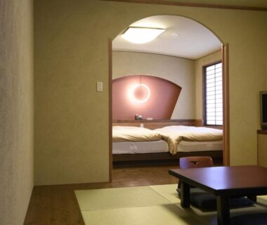 Tatami seating area with low table, archway to twin beds and shoji screen at Yado Kanzan, Gunma