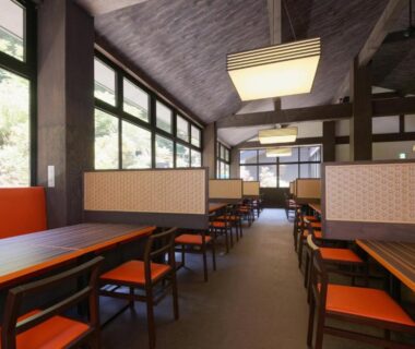 Partitioned dining area with wooden tables and orange chairs at Susukinohara Ichinoyu, Kanagawa