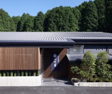 Wooden slatted facade and entrance of Susukinohara Ichinoyu with greenery and forested backdrop in Kanagawa Kanto