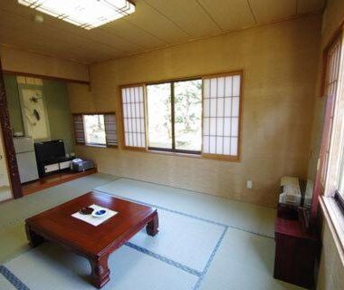 Japanese tatami room with low table, shoji screens and garden view at Suzuki Ryokan Hokkaidō