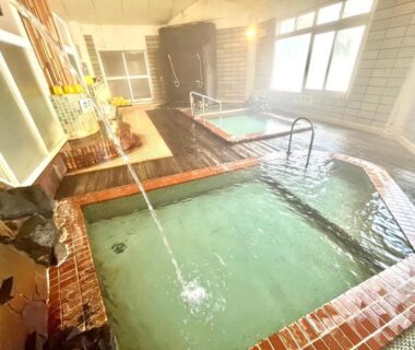 Tiled indoor onsen pools with flowing water and windows at Suzuki Ryokan Hokkaidō