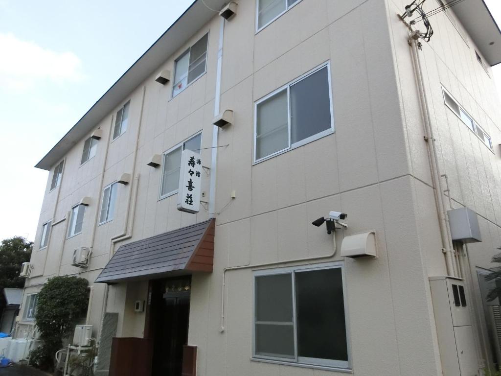 Exterior of Suzukisou Ryokan Kyoto Japan Three-story light-colored exterior with entrance canopy and Japanese signage at Suzukisou ryokan in Kyoto