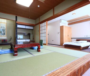 Spacious tatami room with low wooden table, futon bedding, shoji screens and raised sleeping area at Suzunami in Mie
