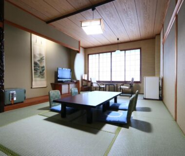 Spacious tatami room with low table, zabuton chairs, shoji window and TV in Suzunami, Mie