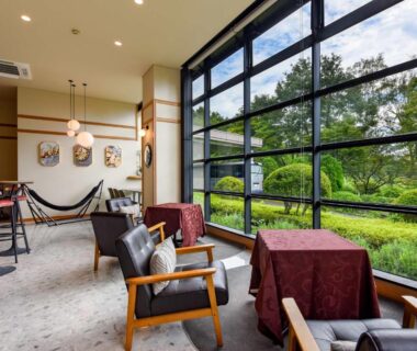 Lounge seating beside large windows overlooking garden at Suzuranso in Nagano