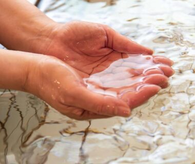 Cupped hands holding clear onsen water at Suzuranso in Nagano