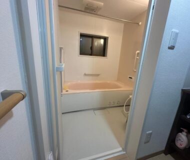 Small bathroom with bathtub, handrail and shower area at Suzuya ryokan in Miyagi