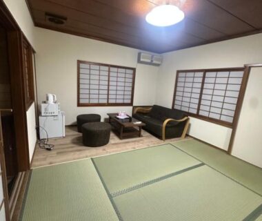 Japanese tatami room with low table, floor chairs, sofa and shoji screens in Suzuya, Miyagi