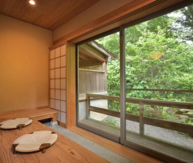 Traditional wooden guest room with shoji screens and balcony overlooking lush greenery at Syoubun, Gunma