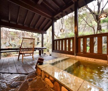 Wooden outdoor onsen bath with deck chair and garden view at Syoubun, Gunma
