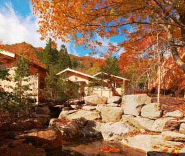 Rocky stream and maple trees beside wooden ryokan cottages at Syoubun in Gunma Kantō mountains